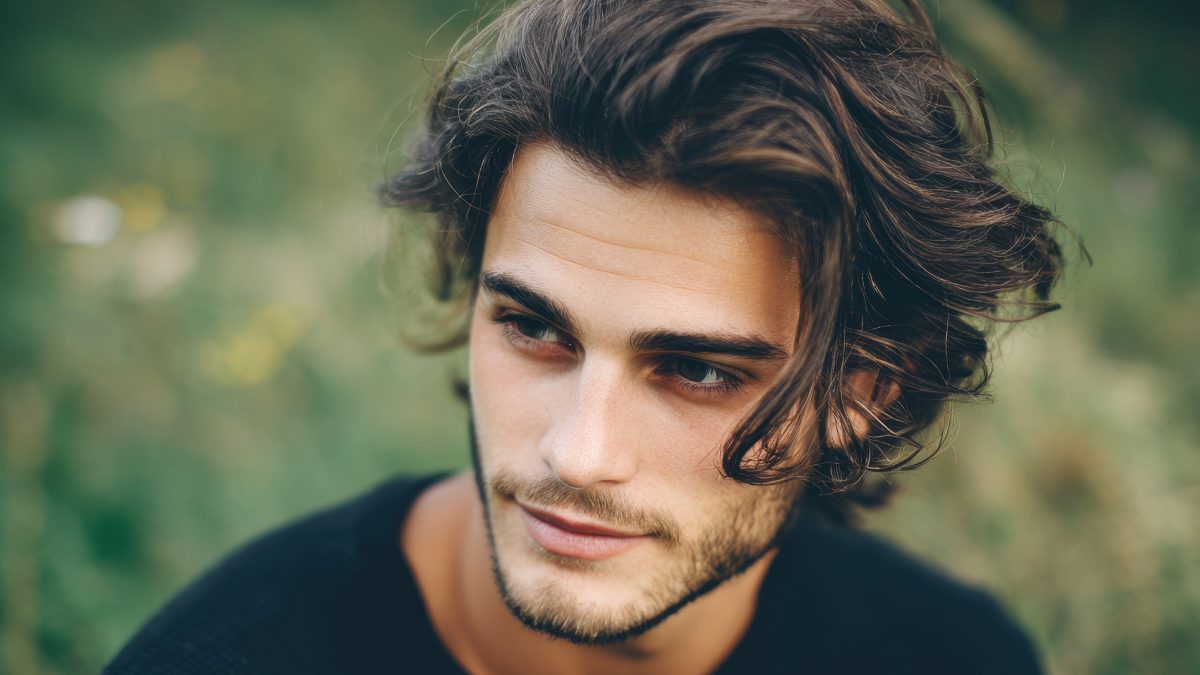 Male creator with long wavy hair and a beard outdoors