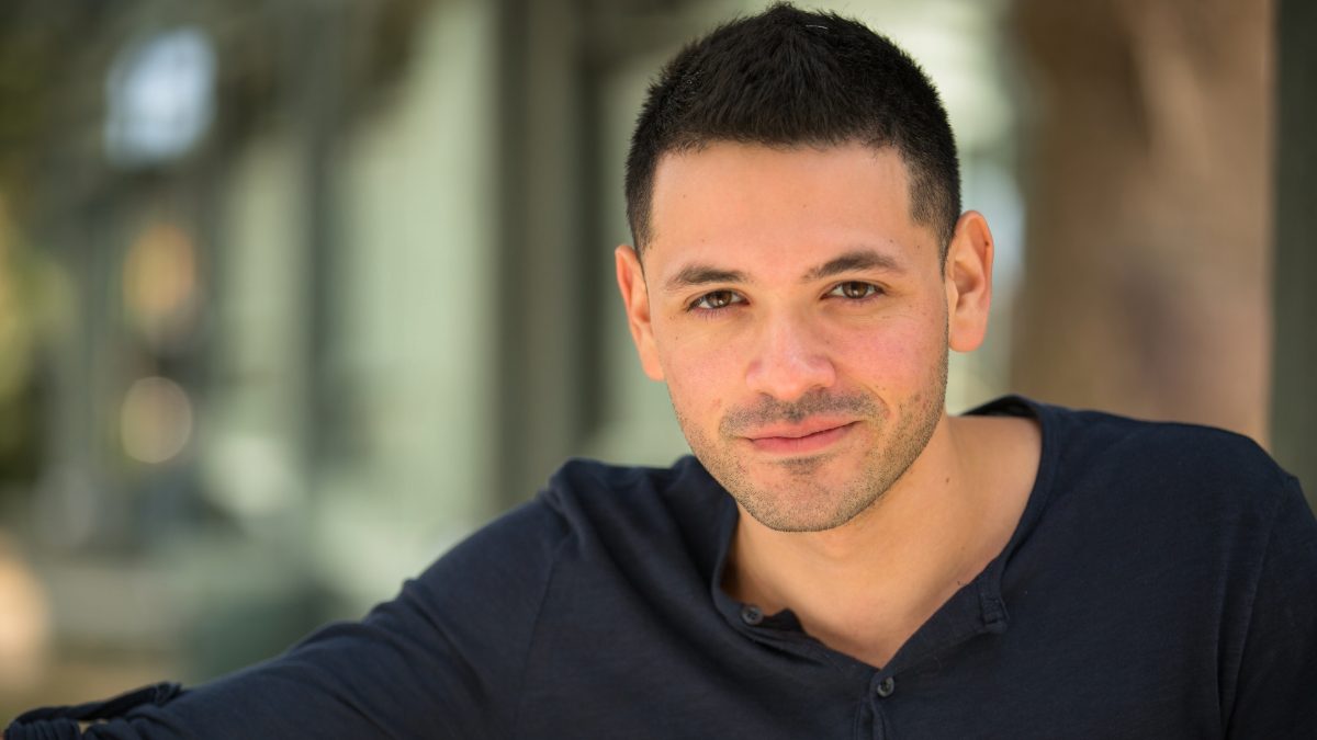 Male creator in a dark shirt smiling in an urban setting