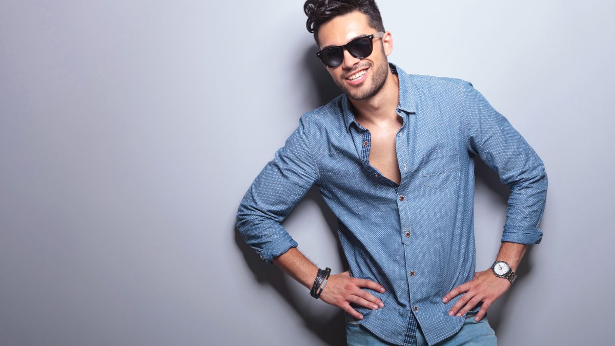 Male creator in a blue shirt and sunglasses with a hand on his hip
